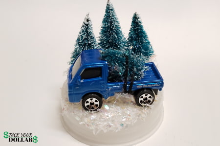 Toy truck glued onto landscape with pine trees and snow